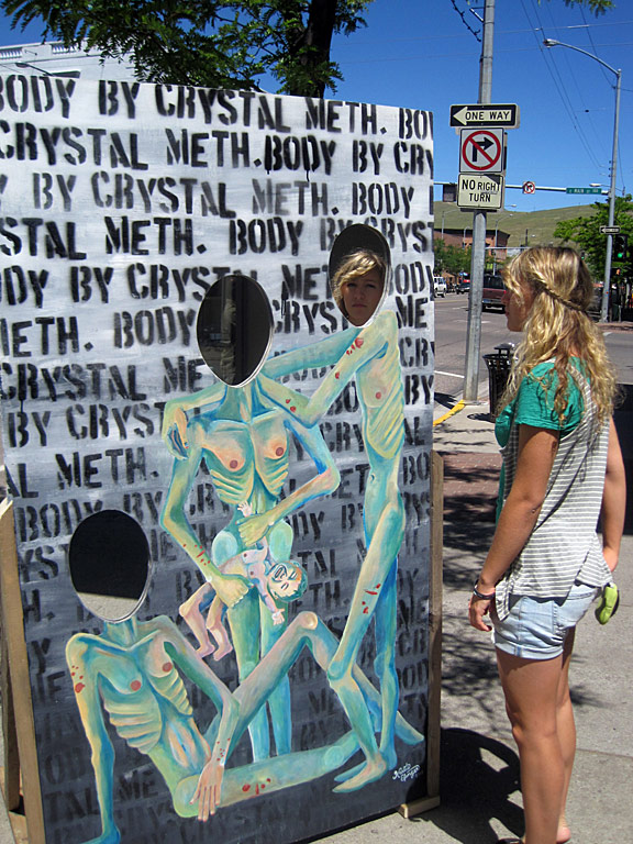 it was on a piece of 7X4 plywood, acrylic paints and spray painted letters w/ a hand made stensil. I installed mirrors in the place of heads to reflect peoples&#039; images. I was inspired by the harmful effects of meth on its user&#039;s bodies and families