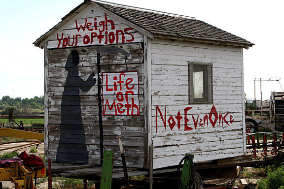 The idea we had in mind was to choose which way you want to spend your life, to make a decision of either living, or letting the dark side of things, and even death, take over. We ended up painting an old shed on the farm our family owns. It's old and faded, with flaking white paint. Just perfect for an anti-meth mural. We worked with very little supplies, (handful of leftover paints, few old brushes, a borrowed ladder, etc.) but were very pleased with the outcome. It's visible from a very popular highway, and we think our message and colors stand out very well. The upper part of the shed says, "Weigh Your Options" and below that is a "Grim Reaper" with his sickle, and dangling from it is a sign that reads, "Life or Meth". Along the side of the shed (the side facing the road directly) we painted in bright red letters, "Not Even Once". I suppose if we had to explain our message we would say, "Weigh your options. You can choose to live, or you can choose to do meth. You can not do both."